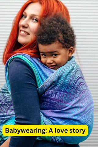 Parent carries child on her back in Long Woven Wrap Peacock's Tail Fantasy. Text reads, "Babywearing: A love story"