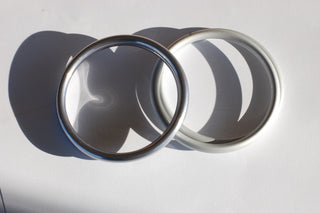 Medium hand-buffed slate sling ring next to medium Silver ring sling