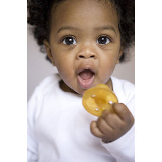 Baby holding Natursutten round rubber Original pacifier. Made in Italy.