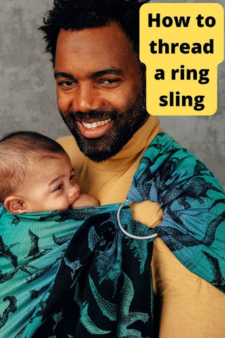 Black father smiles while wearing his Black baby on his chest in a Jurassic Park ring sling available from mama-roo.com. Text reads, "How to thread a ring sling"
