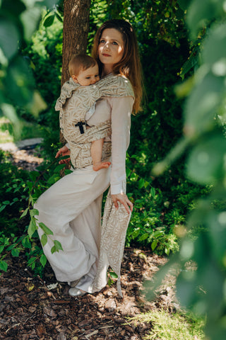 A mom carrying her baby in the LennyLamb Hybrid, Infinity - Golden Hour design. 